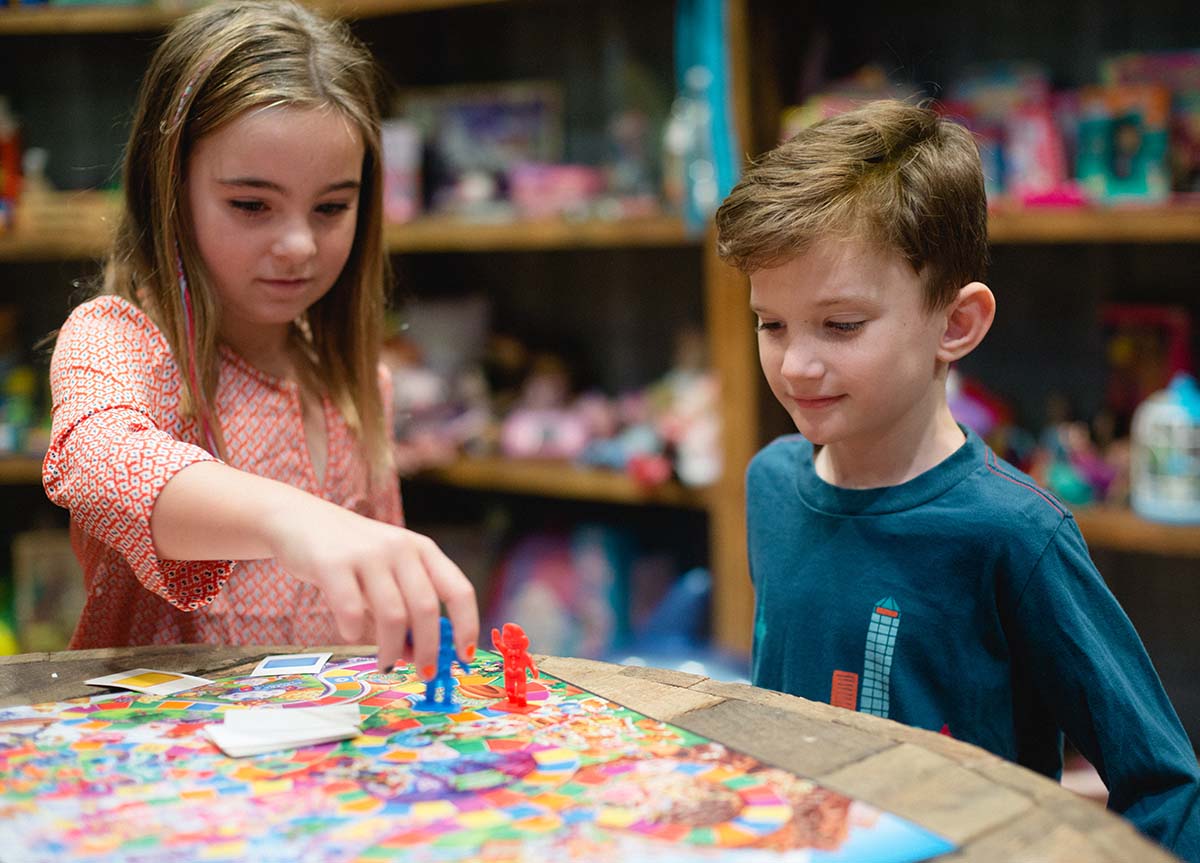 A girl and a boy are playing the board game "Candy Land"
