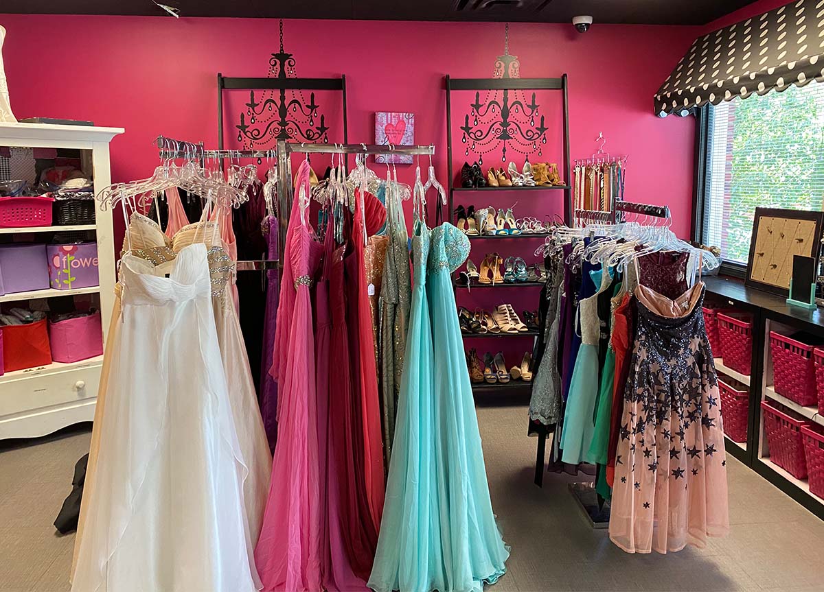 Pink room with a lot of long, beautiful dresses and shoes